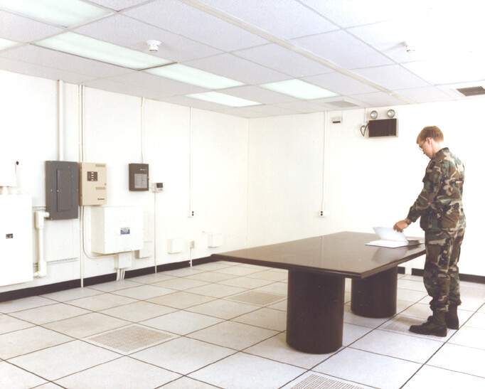mand i uniform står ved bord i aflytningssikkert lokale (SCIF)